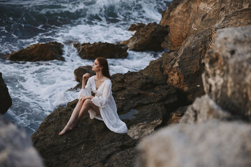 barefoot woman in white dress sits on a stone with wet hair unaltered