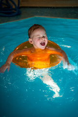 Baby girl in the private home swimming pool in a swimming circle enjoys splashing