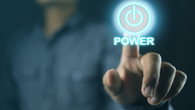 The hand is pressing the power button to activate a future power system or startup. power and start concept.