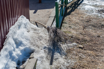 There is a broom with a long wooden handle in the snow