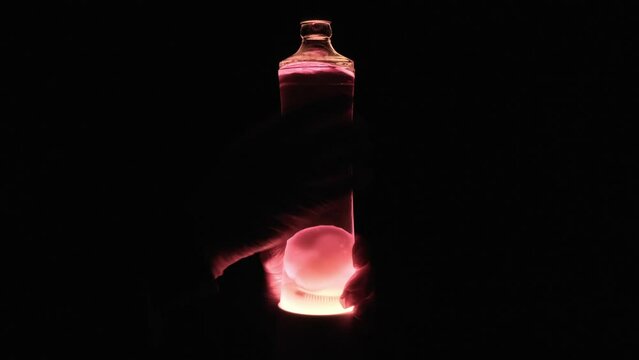 Sex represented with objects: a pair of hands with gloves rubbing a glass bottle with wax on the bottom (hand job), glowing in the darkness. For when you can't show the real thing.
