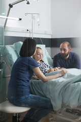 Anxious stressed couple discussing about little girl illness evolution while in pediatric hospital patient recovery ward room. Worried nervous young parents talking about healthcare treatment.