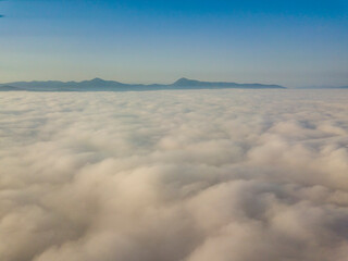 Flight over fog in Ukrainian Carpathians in summer. Mountains on the horizon. Aerial drone view.