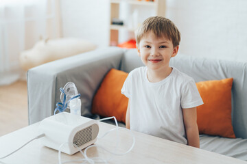 Fototapeta premium Little boy sitting on the couch in front of the nebulizer.