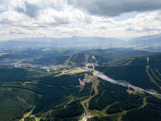 Green slopes of Ukrainian Carpathian mountains in summer. Cloudy morning, low clouds. Aerial drone view.