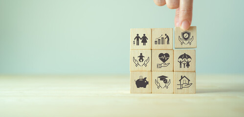 Insurance and stages of life concept.  Hand puts wooden cube with assurance icon standing on...