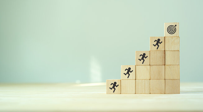 Common goal success concept. Teamwork rises up stairs to goal and achieve successful business. Initiation for planning to reach target. Darts target aim icon on wooden cubes with grey background..