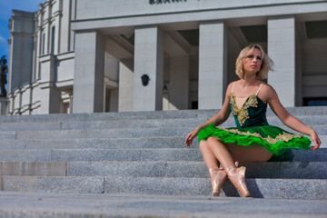 Calm Winsome Elegant Professional Caucasian Ballet Dancer in Green Tutu Dress Posing in Dance On Stairs Outdoor