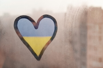 doodle heart shape in colors yellow blue of Ukrainian flag on wet sunset window