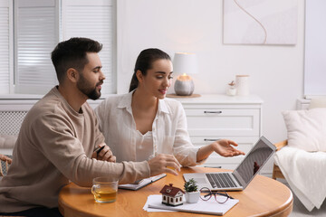 Happy young couple choosing new house using laptop at home. Mortgage concept