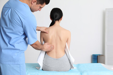 Obraz premium Orthopedist examining woman's back in clinic. Scoliosis treatment