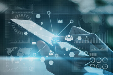 Close up of hand using pad with abstract global digital business interface on blurry background. Interface, chart and hud concept. Double exposure.