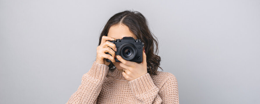 Panorama crop photo of a young woman looking in a modern camera.