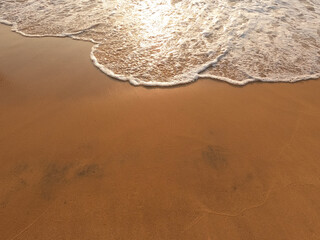 Soft blue ocean wave on a clean sandy beach.