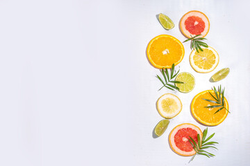 Fototapeta na wymiar Colorful flatlay of citrus fruit slices and tropical palm leaves. Orange, grapefruit, lemon, lime bright high-colored slices on white background. Summer holiday background top view