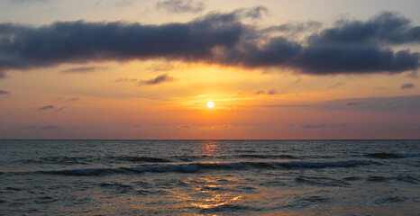 Naklejka na ściany i meble Bright beautiful sunset at the calm sea. Solar disk over water.