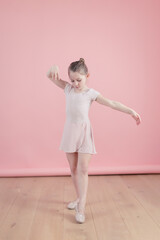 little girl in pink ballerina tutu dancing on pink background
