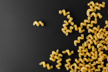 Raw pasta cavatappi with copy space on black background.