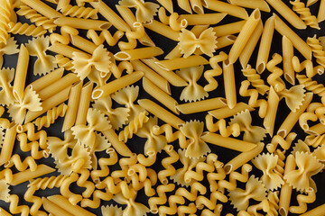 Different kinds of raw pasta texture on black background.