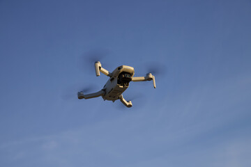 A small drone hovering in the air against the sky.