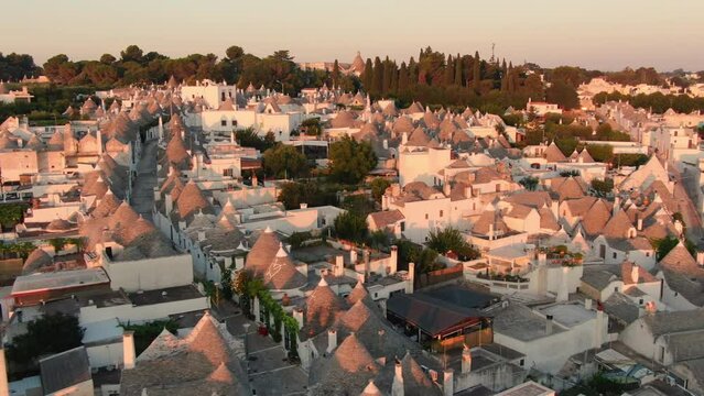 italian landmark trulli di alberobello old town aerial view drone at sunrise,flying sideways over historic city center 4k