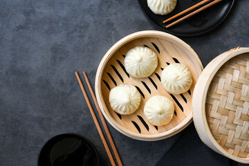 Bamboo steamers with tasty baozi dumplings, chopsticks and bowl of sauce, top view. chinese food, taiwanese food