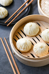 Bamboo steamers with tasty baozi dumplings, chopsticks and bowl of sauce, top view. chinese food,...