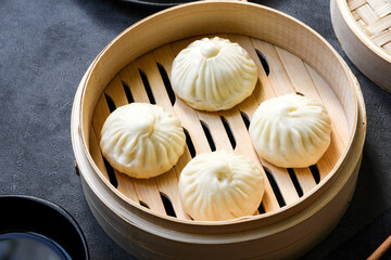 Bamboo steamers with tasty baozi dumplings, chopsticks and bowl of sauce, top view. chinese food, taiwanese food