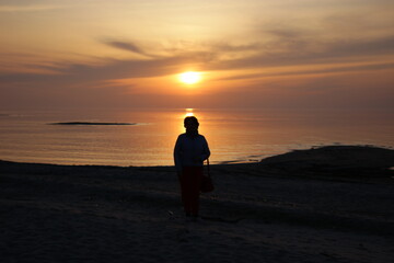 Fototapeta premium silhouette of a person walking on the beach at sunset