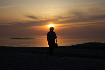 Fototapeta premium silhouette of a person standing on the beach at sunset