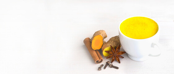 Golden Milk drink with ginger, turmeric and other  spices on white banner background. Alternative remedies for preventive illness and strong immune system