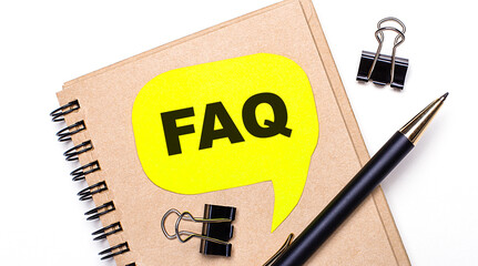 On a light background, a brown notebook, a black pen and paper clips, and a yellow card with the...