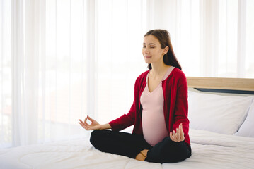 Fototapeta na wymiar Pregnant woman sitting on bed and practice yoga in modern bedroom.