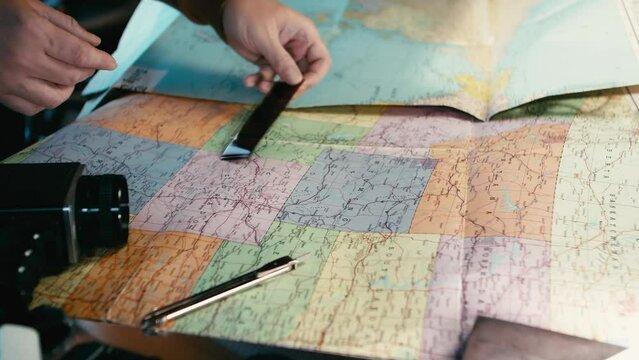 A traveler looks at the negatives of photos on celluloid film and searches for the places visited on a map.
