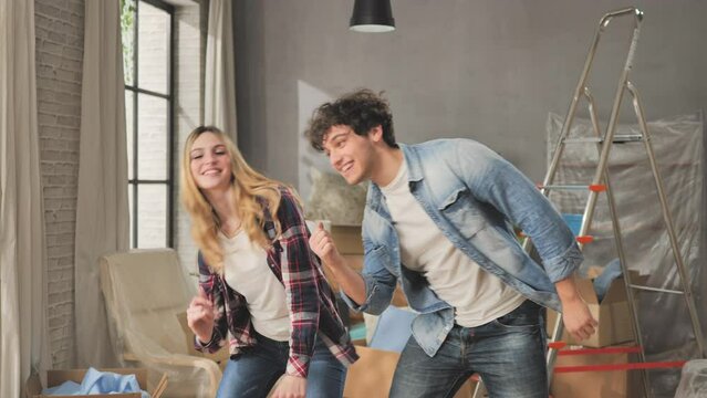 Excited young couple moving to new house having fun dancing celebrating new apartment,happy roommates dance and celebrate the renovation of the home 4k