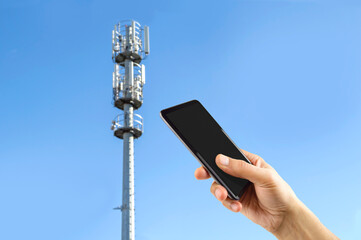 Closeup of hand using phone phone tower cellular sky background.