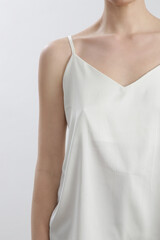 Woman in white silk satin camisole shirt, studio shot.