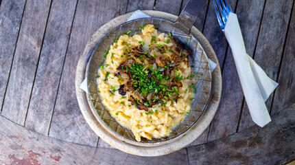 Selbstgemachte Käsespätzle Knöpfle mit Zwiebeln in einer Eisenguss Pfanne im Biergarten  