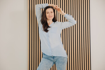 Image of happy young business woman posing on a wooden wall background. acoustic panels in the...