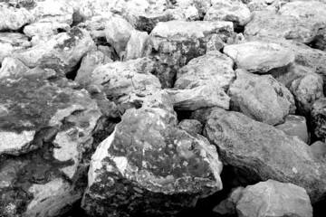 Stones used as breakwater at the sea in black and white.