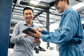 Fototapeta na wymiar Asian automotive mechanic explain car condition to client in garage. 