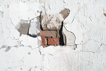 Destroyed stucco brick wall in middle, uneven textured gray surface with cracks and scuffs