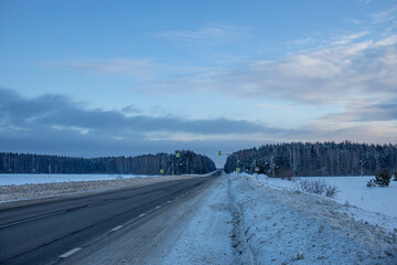 Obraz premium Winter evening landscape, road in the foreground. Sunset sky over the horizon.