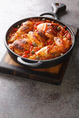 Mediterranean chicken baked with tomatoes, peppers, onions and garlic close-up in a frying pan on the table. vertical