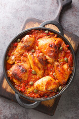 Mediterranean chicken baked with tomatoes, peppers, onions and garlic close-up in a frying pan on the table. vertical top view from above