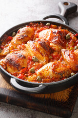 Baked chicken with sofrito vegetable sauce close-up in a frying pan on the table. vertical