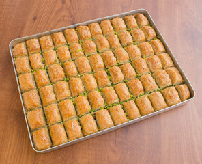 A tray of sliced tasty Turkish Baklava garnished with pistachio nut on marbel background. Sliced pistachio Baklava pieces on a tray on marbel background. Traditional Turkish Baklava with pistachio.