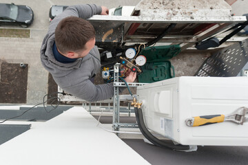 the worker carries out installation of the conditioner being in the basket of the high-rise elevator
