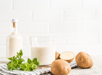 alterative potato vegetable milk. glass bottles against a white brick wall. the concept of a...