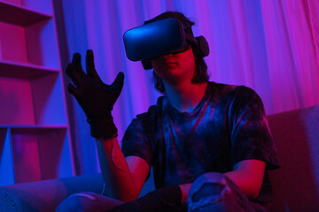 Metaverse technology concept, Man wear VR goggles and glove to making gesture while playing games